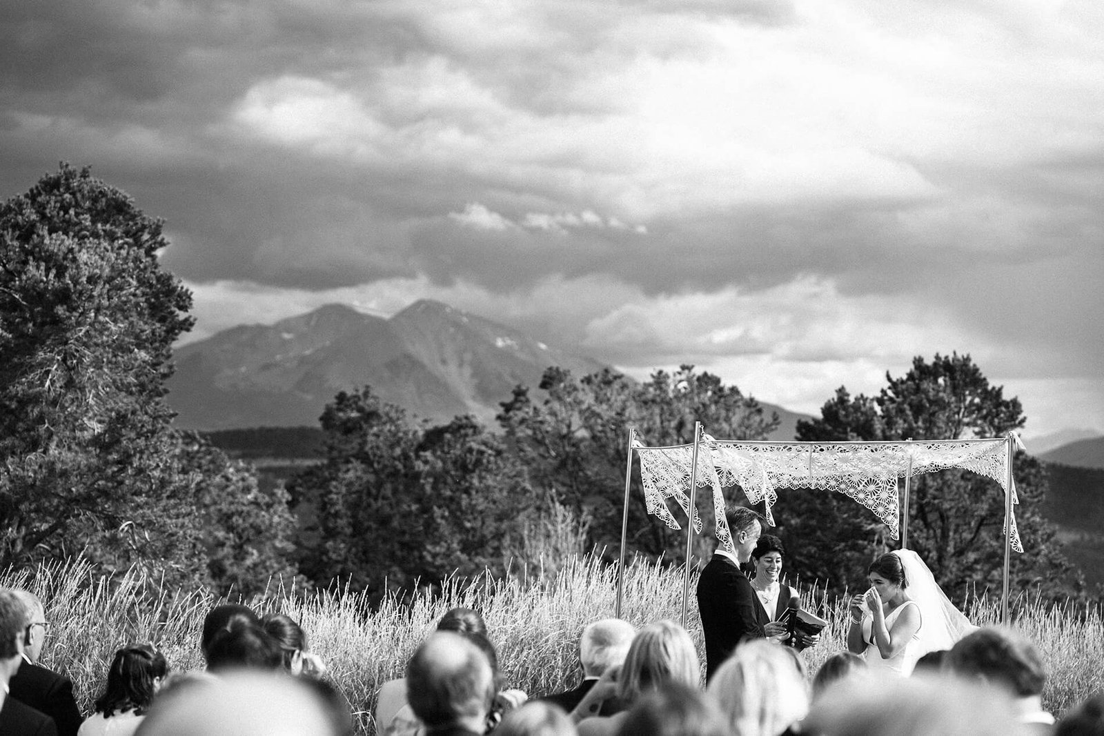 emotional bride with groom under chuppah with mountain peak in the background