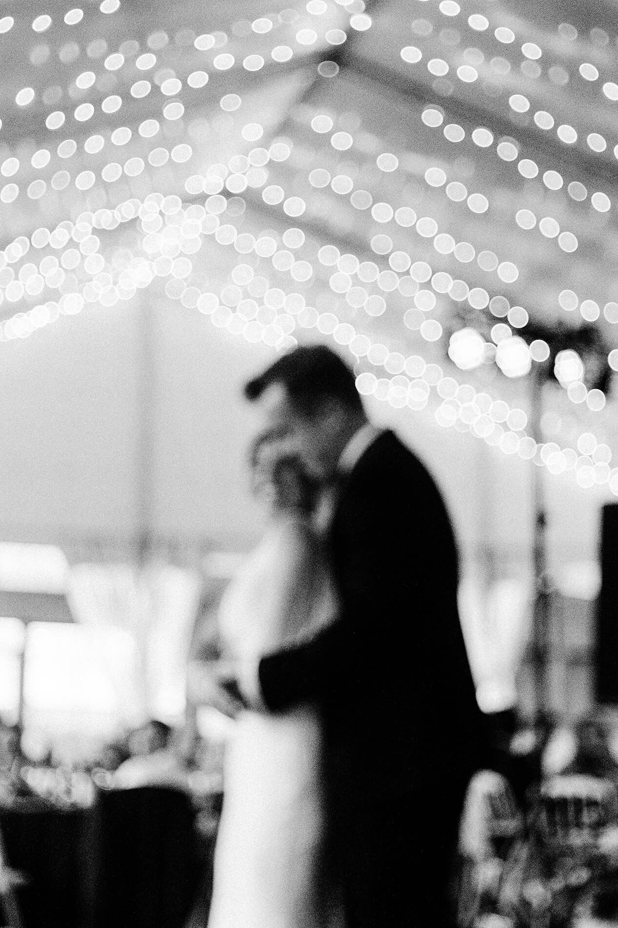 out of focus bride and groom first dance under canopy of lights